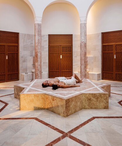 Paar liegt am sternenförmigen Nabelstein und genießt die Wärme in der Oriental World des Spa Resort Geinberg | © Spa Resort Geinberg / Chris Perkles