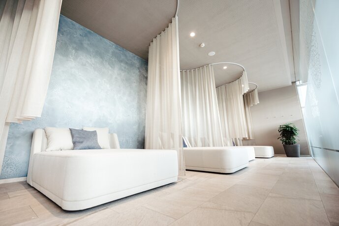 Bequeme Doppelliegen vor hellblauer Wand im hellen Liegebereich des SPAplus | © Spa Resort Geinberg / Tobi Gast