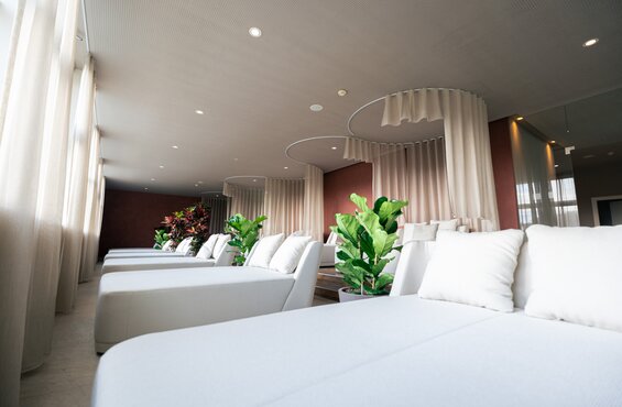 Komfortable Premium-Liegen, umgeben von großen Pflanzen, im Liegebereich des SPAplus | © Spa Resort Geinberg / Tobi Gast