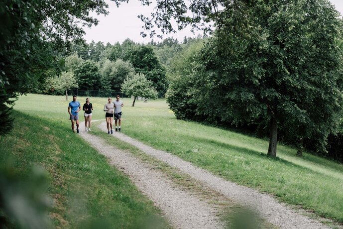 Personengruppe läuft in Sportkleidung durch die grüne Landschaft in Geinberg | © Spa Resort Geinberg / Chris Perkles