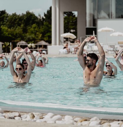 Gruppe beim Aqua-Fitness im Pool, Arme über dem Kopf verschränkt