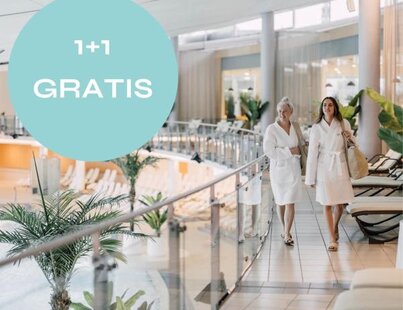 Zwei Frauen in Bademänteln gehen in einem Spa an einem Geländer entlang