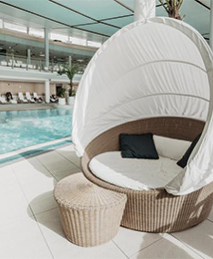 Modernes Rattan-Tagesbett am hellen Hotelpool