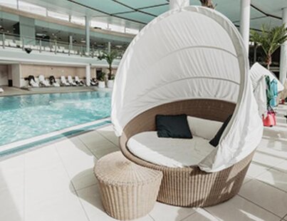 Modernes Rattan-Tagesbett am hellen Hotelpool