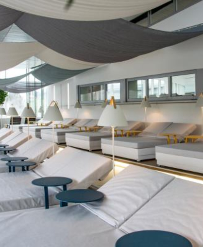 Helle, moderne Liegen in geräumigem Ruheraum mit kleinen Tischen und Lampen