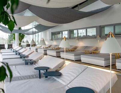 Helle, moderne Liegen in geräumigem Ruheraum mit kleinen Tischen und Lampen