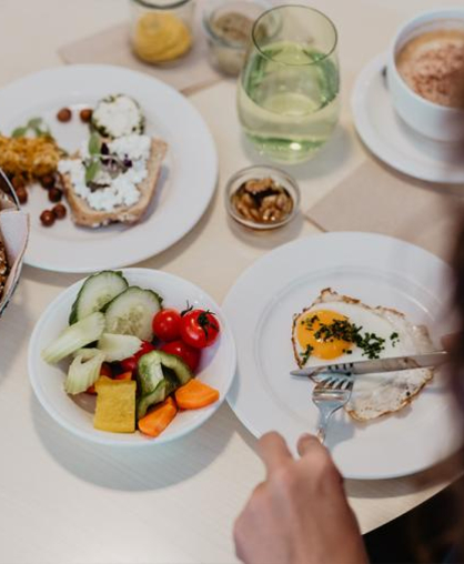 Person isst reichhaltiges Frühstück am Tisch