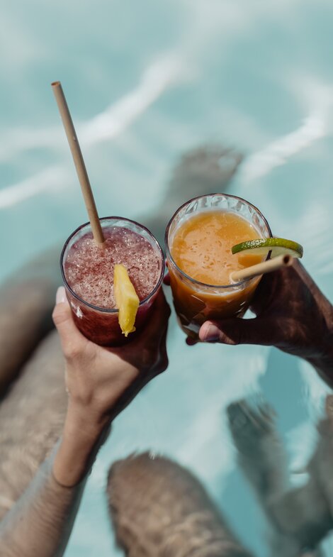 Zwei Personen genießen ihren fruchtigen Cocktail im Pool der Karibik-Lagune im Spa Resort Geinberg | © Spa Resort Geinberg / Chris Perkles