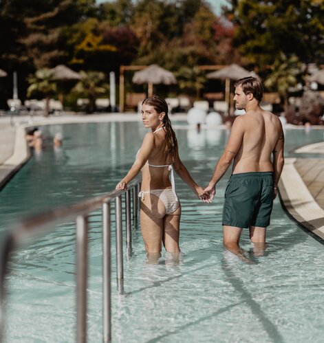 Paar geht Hand in Hand ins Wasser der Karibik-Lagune im Spa Resort Geinberg | © Spa Resort Geinberg / Chris Perkles
