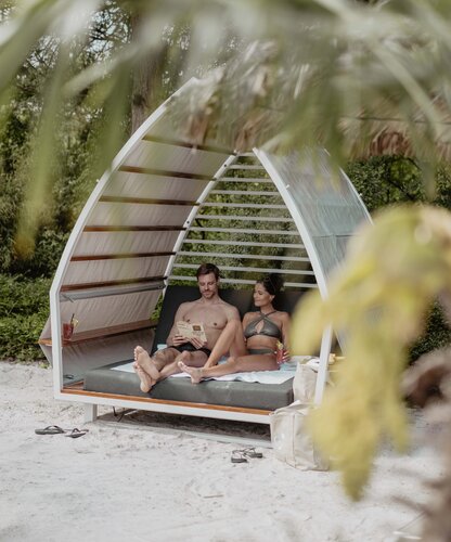 Paar entspannt in Strand-Chalet mit Karibik-Lagune im Spa Resort Geinberg | © Spa Resort Geinberg / Chris Perkles