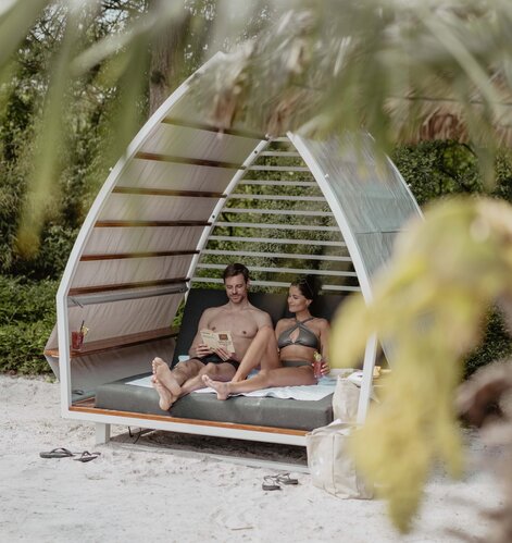Paar entspannt in Strand-Chalet mit Karibik-Lagune im Spa Resort Geinberg | © Spa Resort Geinberg / Chris Perkles