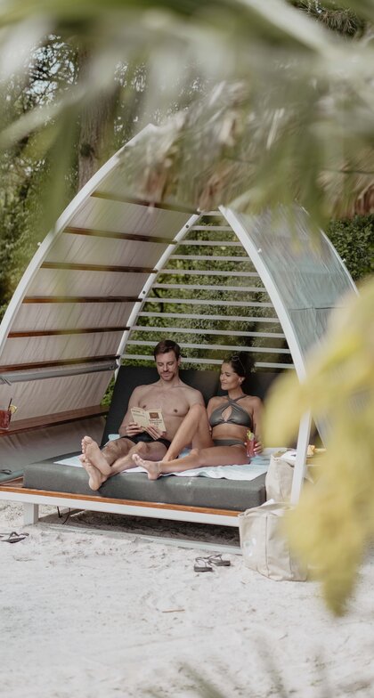 Paar entspannt in Strand-Chalet mit Karibik-Lagune im Spa Resort Geinberg | © Spa Resort Geinberg / Chris Perkles