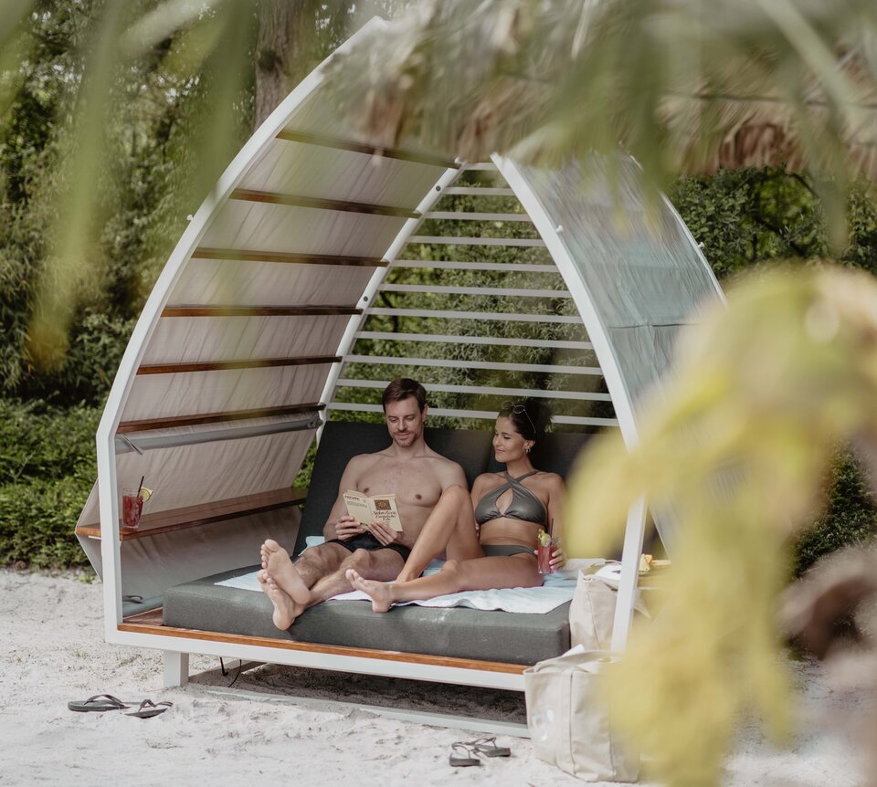 Paar entspannt in Strand-Chalet mit Karibik-Lagune im Spa Resort Geinberg | © Spa Resort Geinberg / Chris Perkles