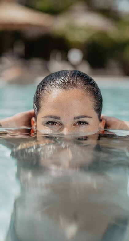 Frau im Wasser, Hände am Beckenrand, Blick in die Kamera | © Spa Resort Geinberg / Chris Perkles