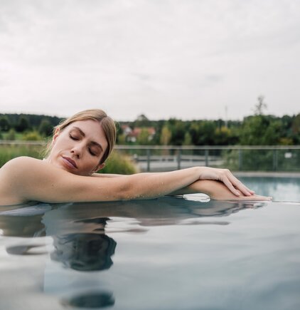 Frau entspannt im Thermalwasser des Kaskaden-Beckens im Spa Resort Geinberg | © Spa Resort Geinberg / Chris Perkles