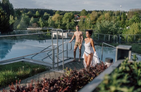 Paar am Kaskadenbecken im Spa Resort Geinberg, Frau im Badeanzug, Mann barfuß | © Spa Resort Geinberg / Chris Perkles