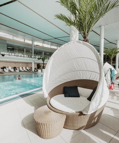 Runder Korbsessel mit Baldachin neben Pool in Therme Geinberg