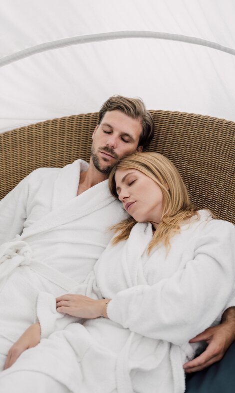 Paar im Bademantel entspannt mit geschlossenen Augen im Relaxation Korb des Spa Resort Geinberg | © Spa Resort Geinberg / Chris Perkles