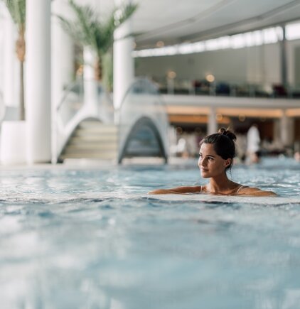 Frau entspannt im wohltuenden Thermalwasser des Thermal-Beckens indoor der Therme Geinberg | © Spa Resort Geinberg / Chris Perkles