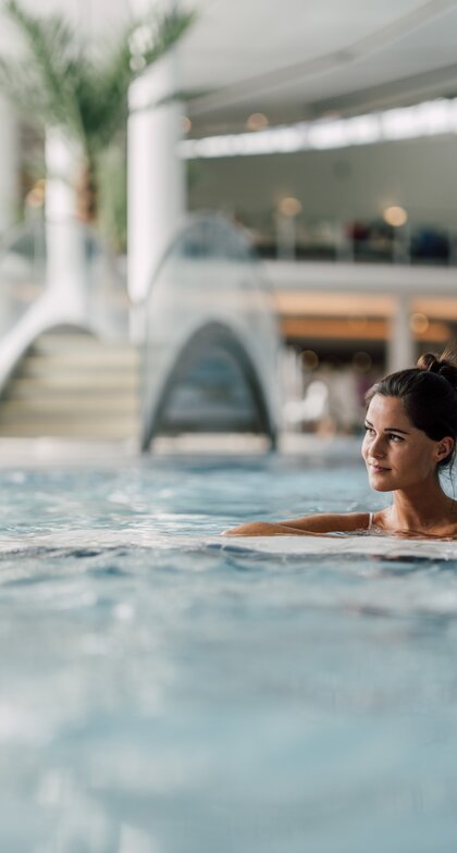 Frau entspannt im wohltuenden Thermalwasser des Thermal-Beckens indoor der Therme Geinberg | © Spa Resort Geinberg / Chris Perkles