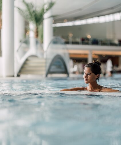 Frau entspannt im wohltuenden Thermalwasser des Thermal-Beckens indoor der Therme Geinberg | © Spa Resort Geinberg / Chris Perkles