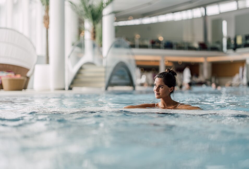 Frau entspannt im wohltuenden Thermalwasser des Thermal-Beckens indoor der Therme Geinberg | © Spa Resort Geinberg / Chris Perkles