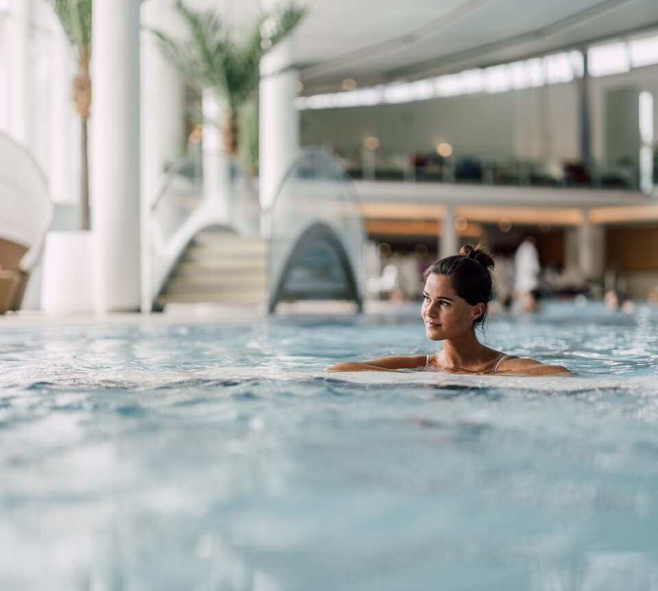 Frau entspannt im wohltuenden Thermalwasser des Thermal-Beckens indoor der Therme Geinberg | © Spa Resort Geinberg / Chris Perkles