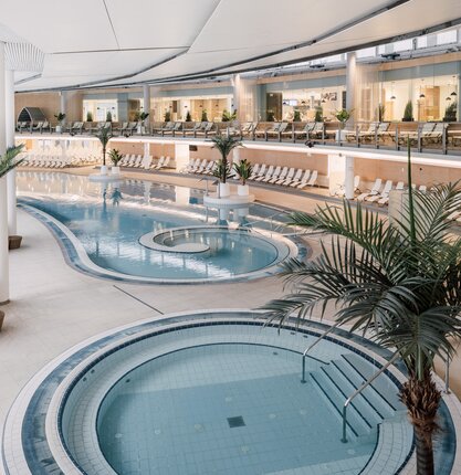 Innenansicht der Therme Geinberg mit Becken, Liegen und Palmen | © Spa Resort Geinberg / Chris Perkles