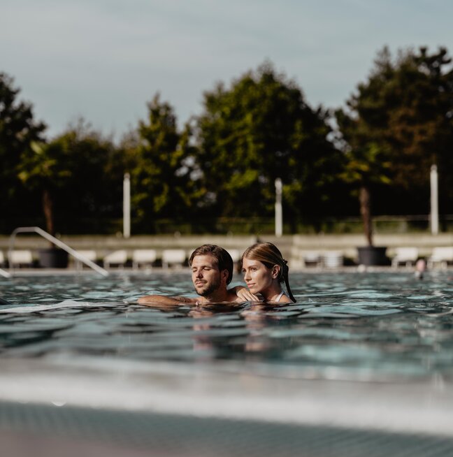 Paar entspannt gemeinsam im Thermal-Becken outdoor des Spa Resort Geinberg | © Spa Resort Geinberg / Chris Perkles