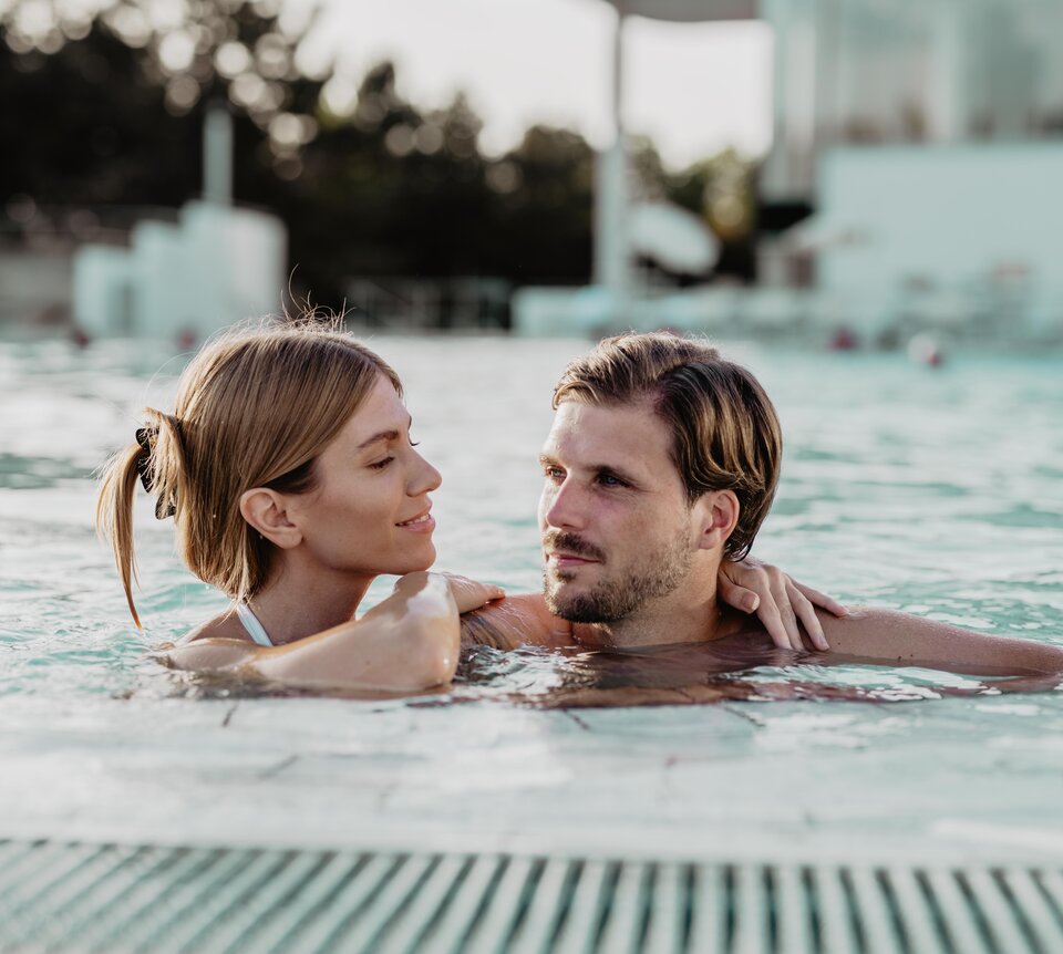 Vertrautes Paar entspannt Arm in Arm im Thermal-Becken outdoor des Spa Resort Geinberg | © Spa Resort Geinberg / Chris Perkles