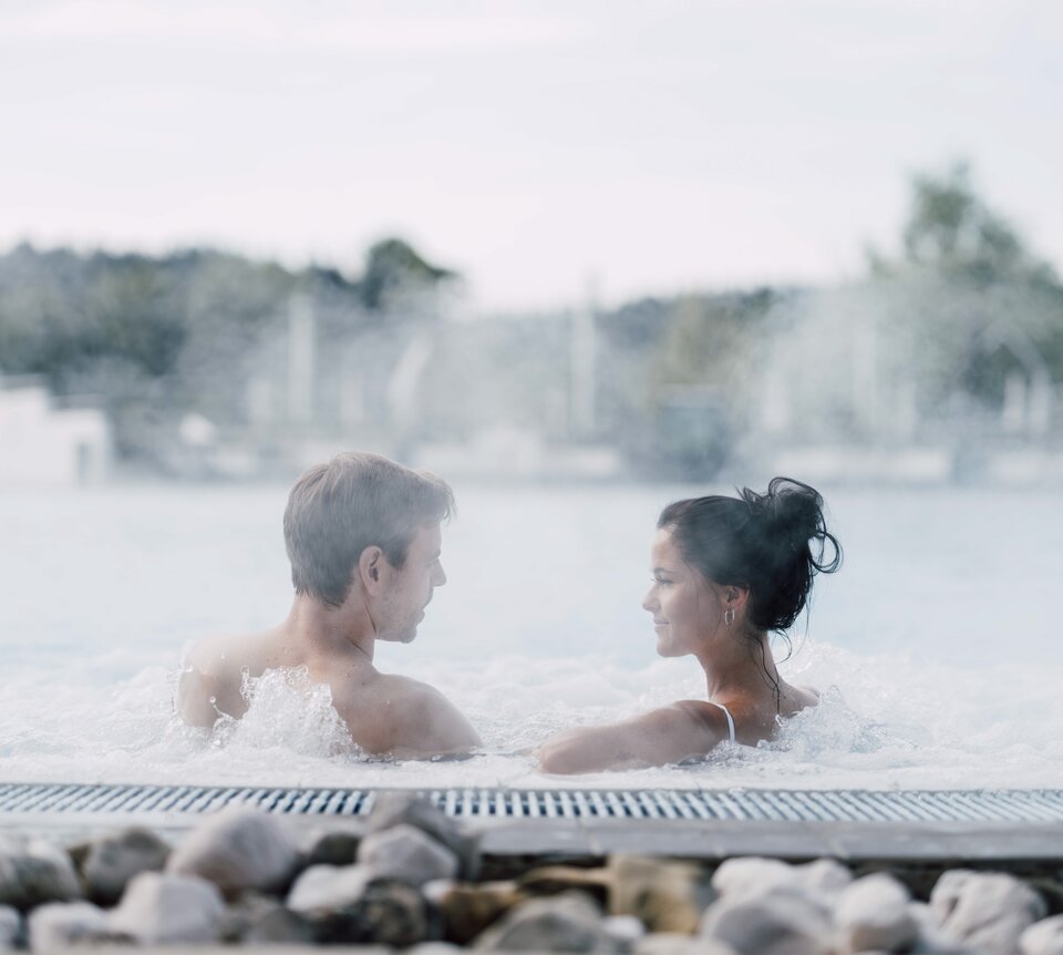Paar entspannt im warmen Außenbecken der Therme Geinberg | © Spa Resort Geinberg / Chris Perkles
