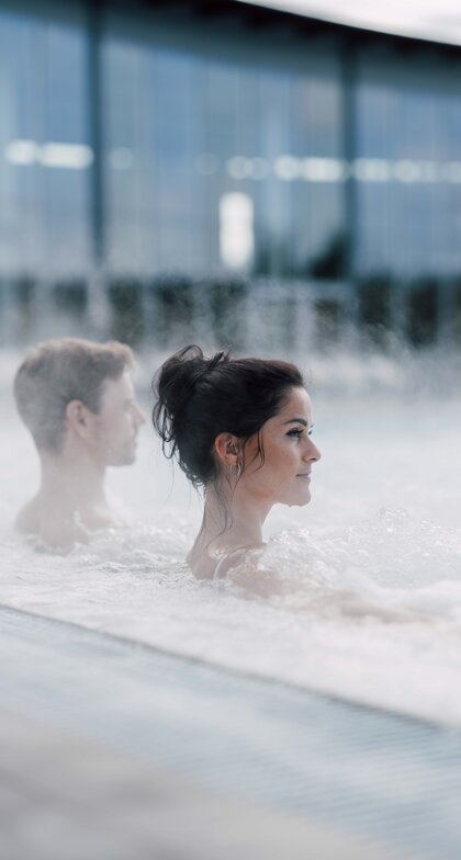 Paar im Thermalbecken im Freien, Dampf steigt auf | © Spa Resort Geinberg / Chris Perkles