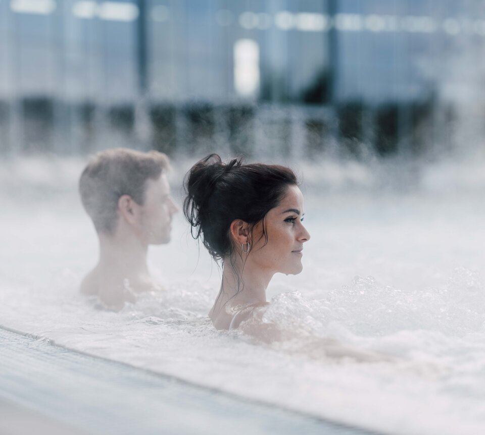 Paar im Thermalbecken im Freien, Dampf steigt auf | © Spa Resort Geinberg / Chris Perkles