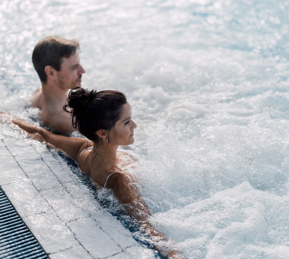Paar entspannt im sprudelnden Thermalbecken im Freien des Spa Resort Geinberg | © Spa Resort Geinberg / Chris Perkles