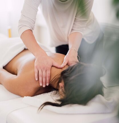 Frau liegt auf Massageliege, Masseurin massiert Nacken | © Spa Resort Geinberg / Chris Perkles