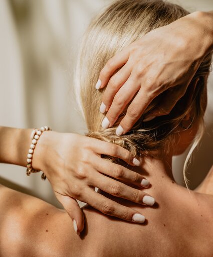 Blonde Dame streicht sich die Haare aus dem Nacken und fühlt sich vollkommen wohl im Vitality Spa | © Spa Resort Geinberg / Chris Perkles